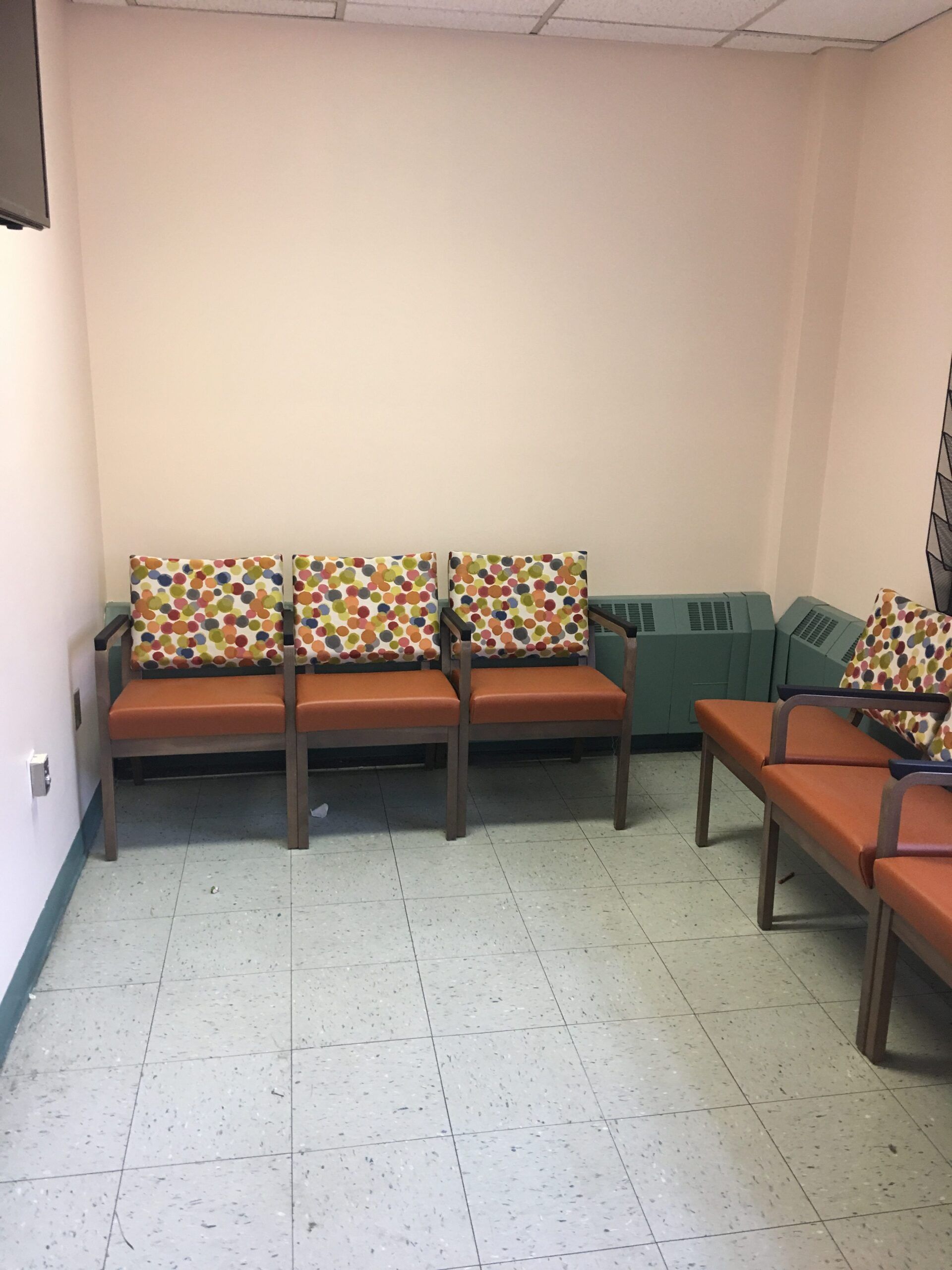 A waiting room with chairs and a tv on the wall