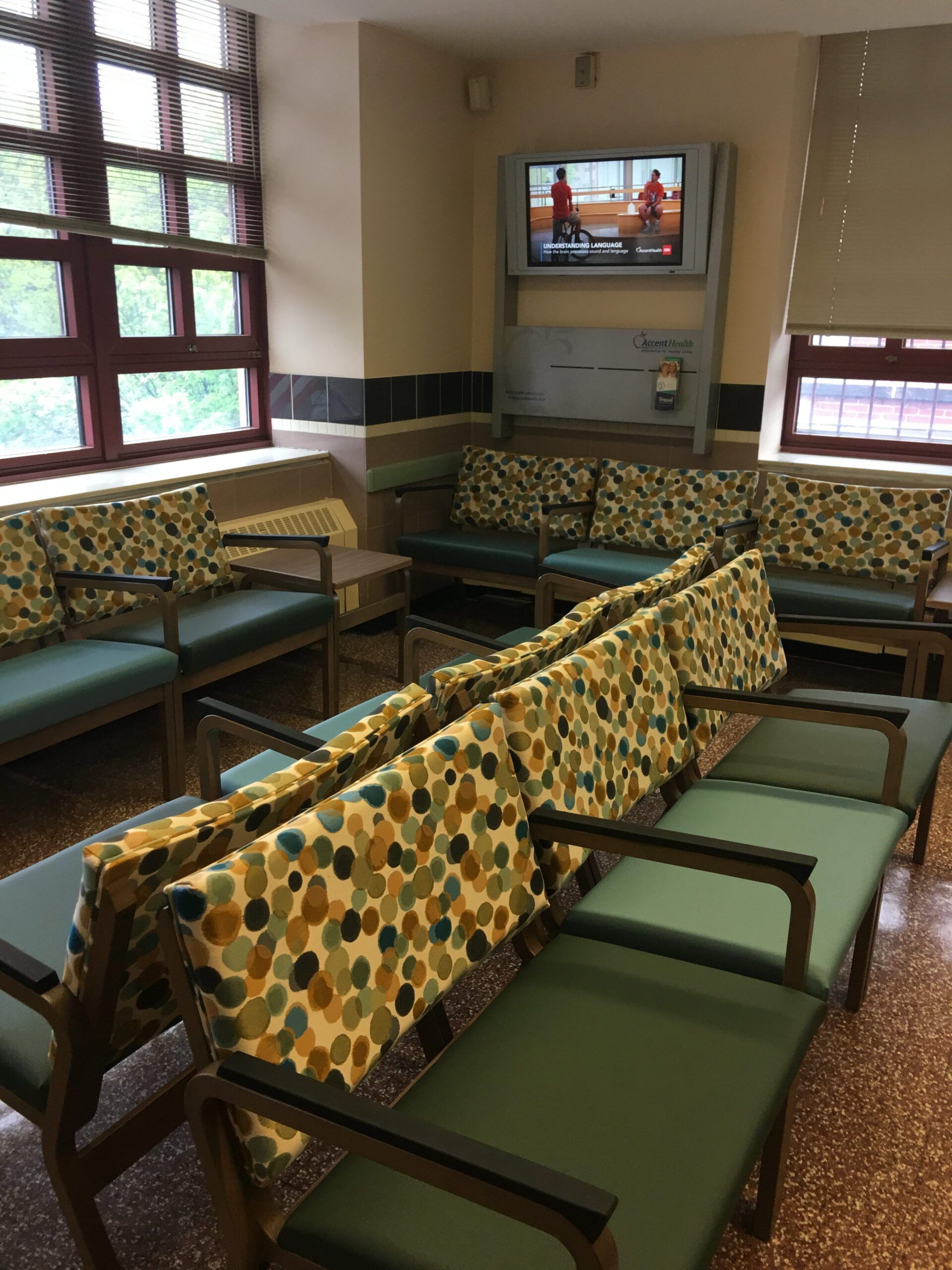 A waiting room with lots of chairs and a television on the wall