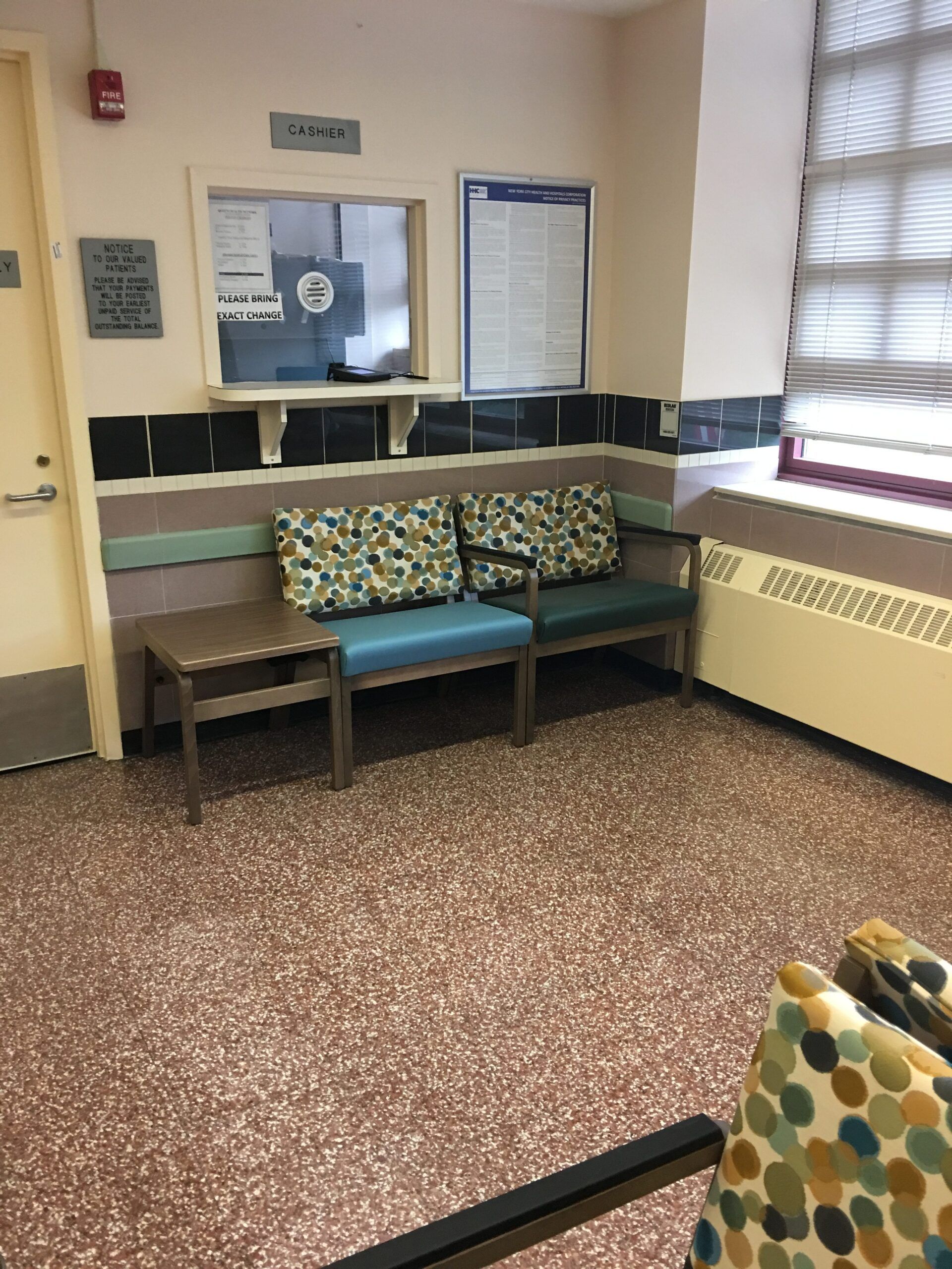 A waiting room with a couch and chairs and a window