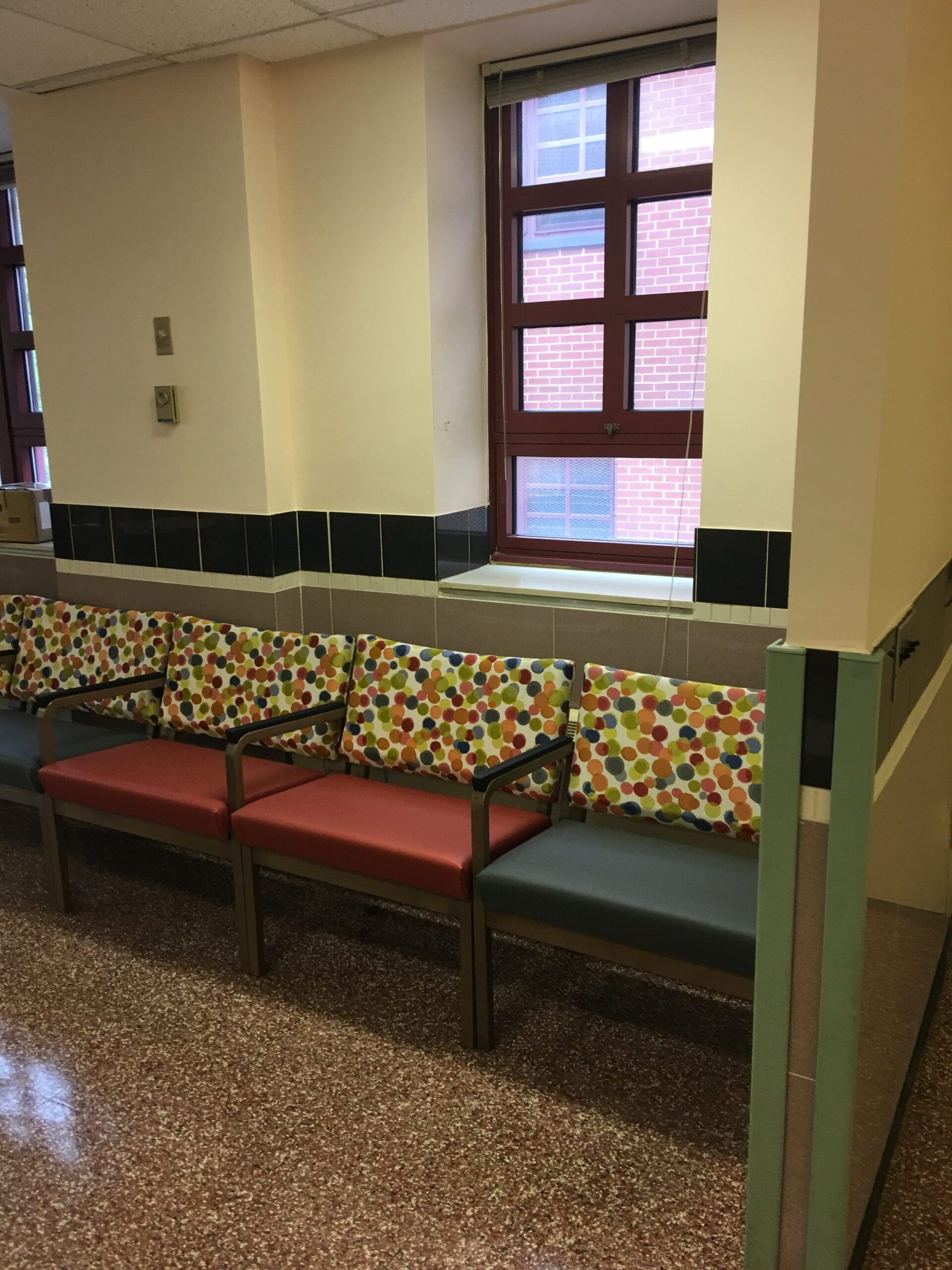 A row of colorful chairs in a hallway next to a window