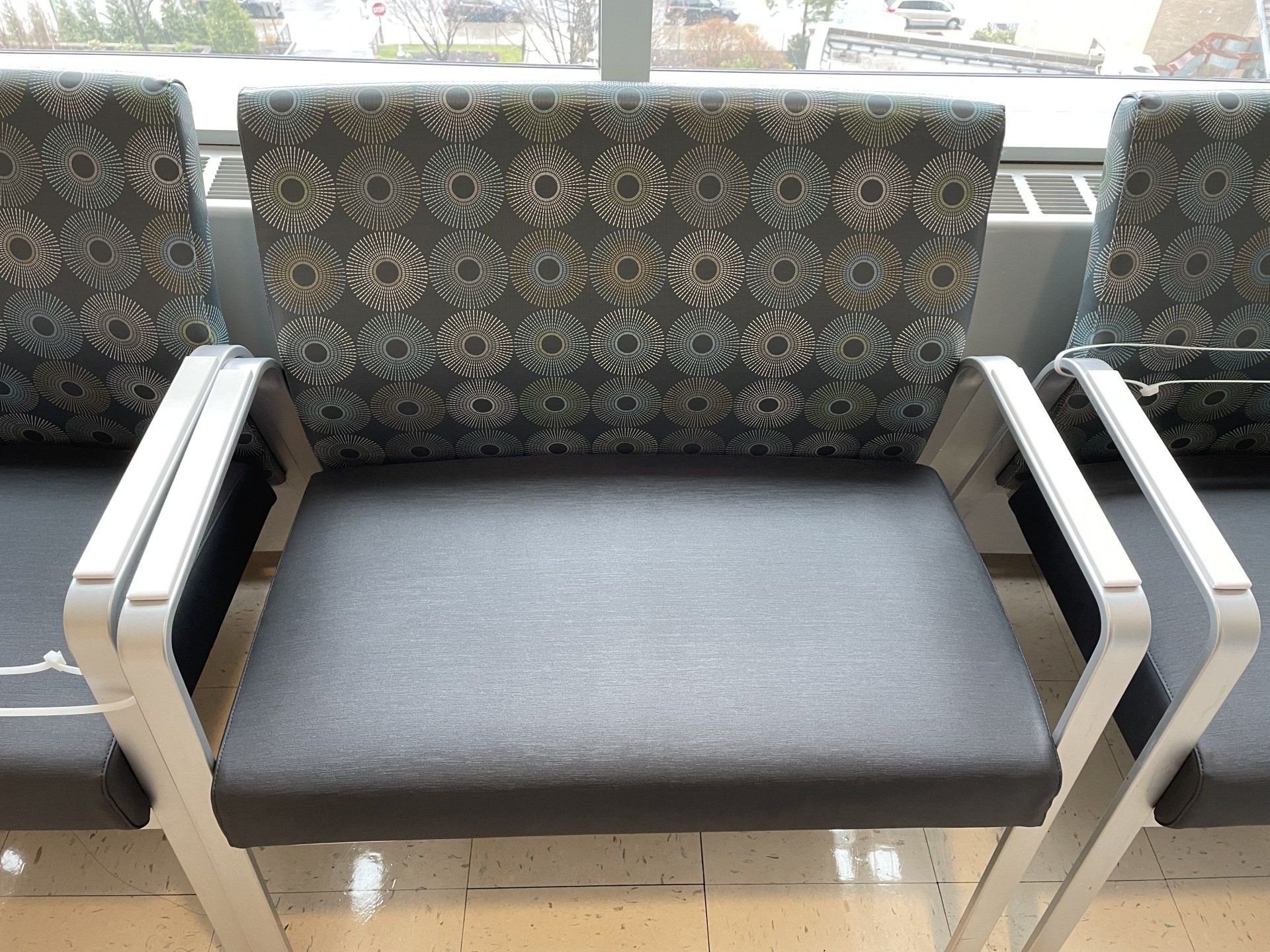 A row of chairs in a waiting room with a window in the background