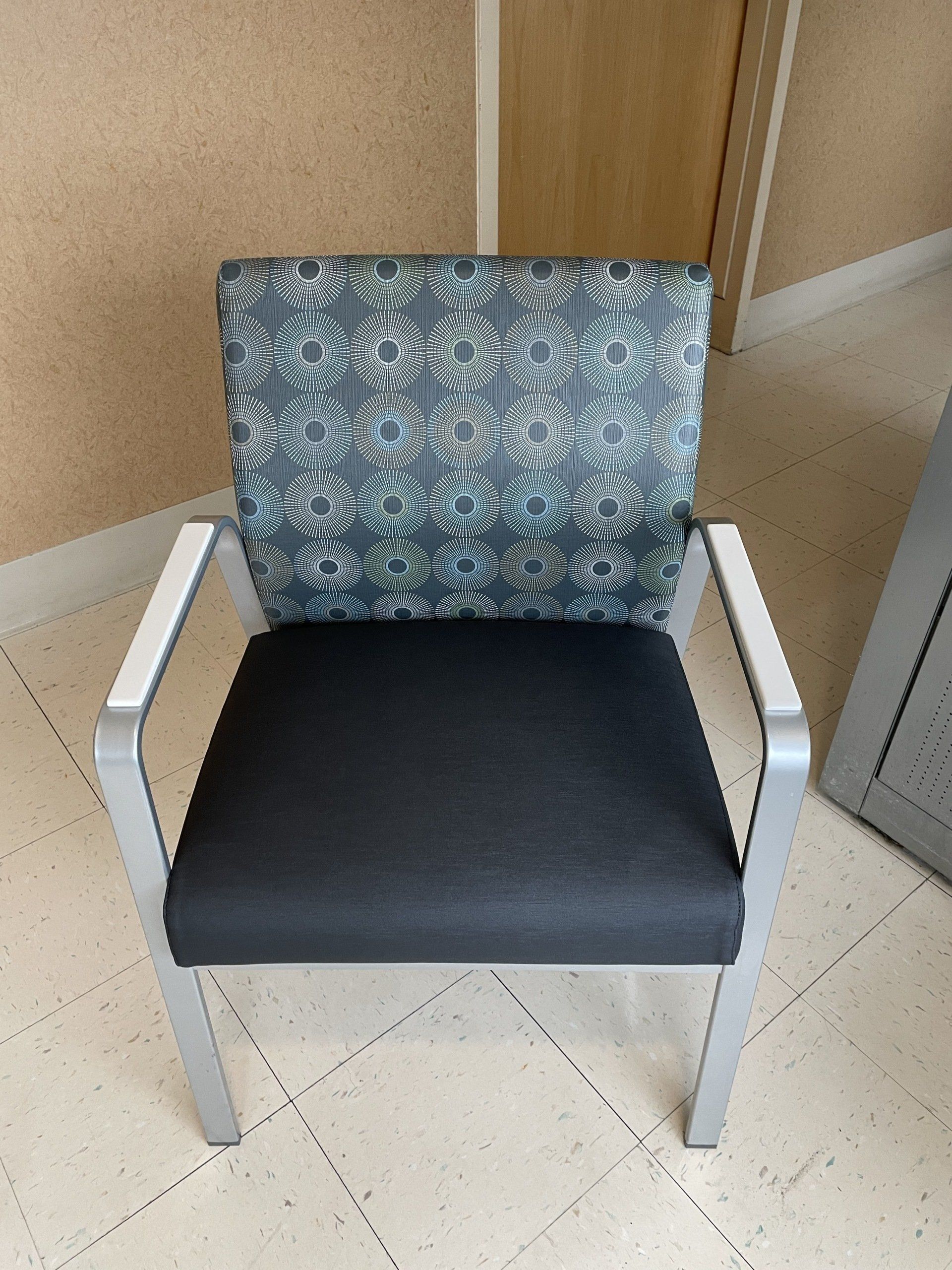 A chair with a pattern on the back sits on a tiled floor