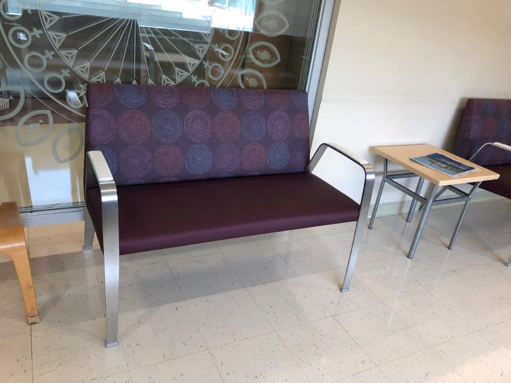 A purple couch in a waiting room next to a table
