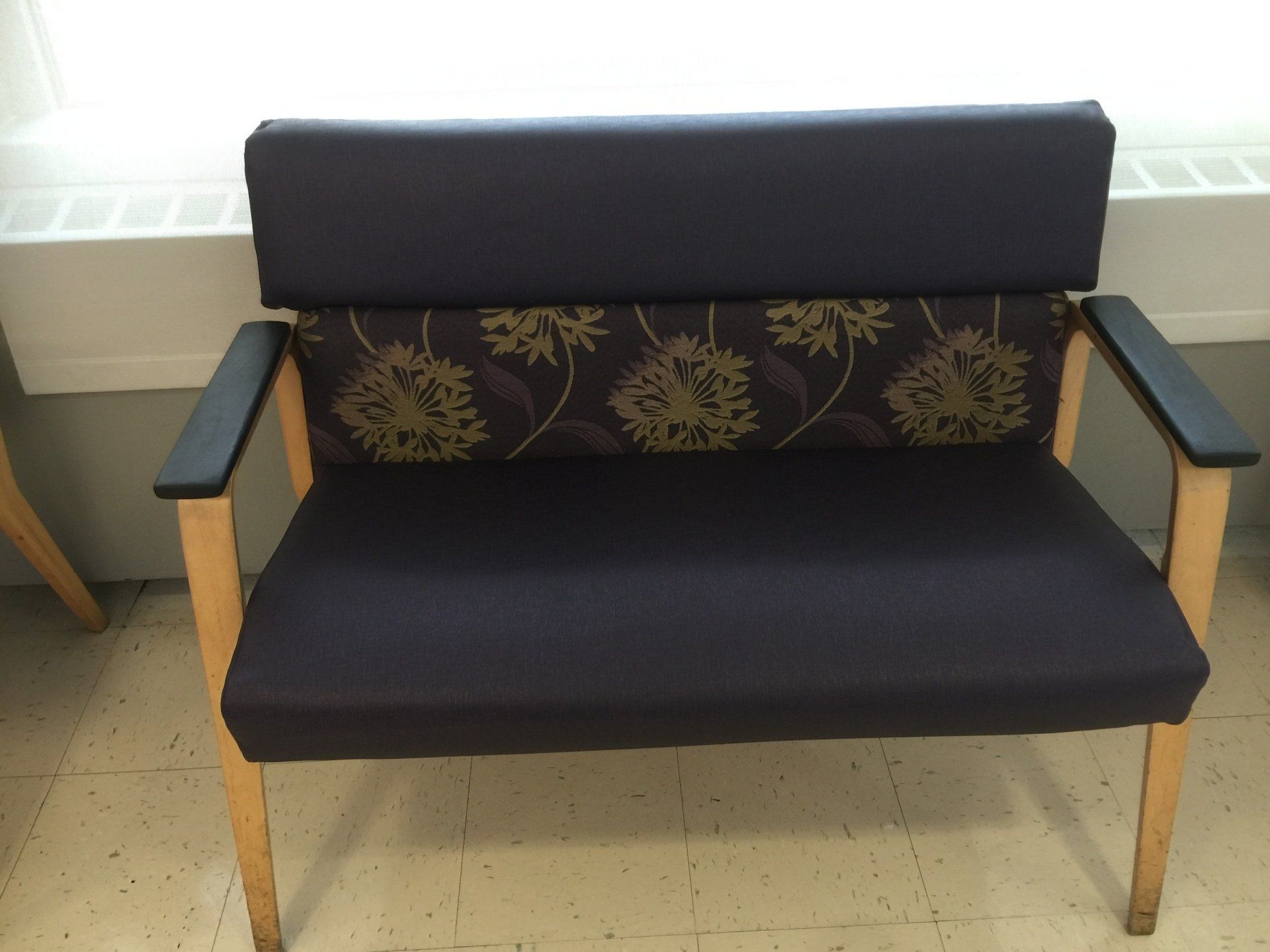 A chair with a floral pattern on the back sits on a tiled floor