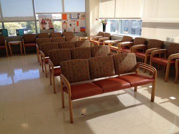 A waiting room with rows of chairs and a bench