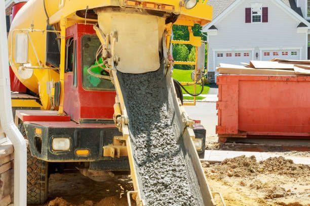 A mixer truck is pouring fresh concrete into a foundation in a housing development.