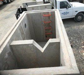 Concrete pit with orange ladder, V-shaped notch. White truck in background.