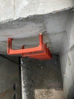 Orange metal handholds installed on a concrete wall; likely a utility or service access.