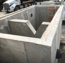 Concrete precast stormwater treatment unit with internal baffle. Truck in background.