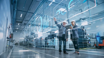 Two people in hard hats reviewing a futuristic factory dashboard in a bright industrial facility