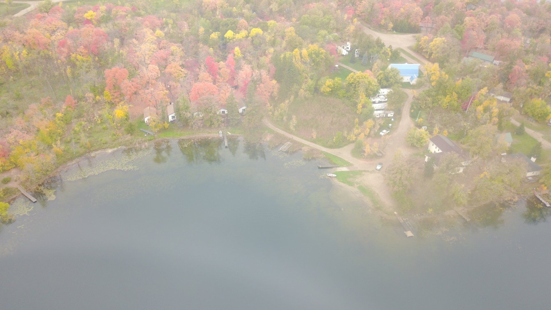 An aerial view of a lake surrounded by trees on a foggy day.