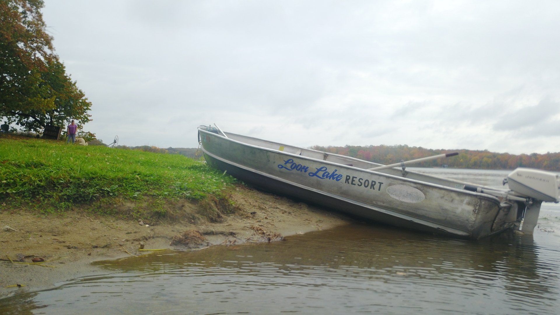 A boat is sitting on the shore of a lake.