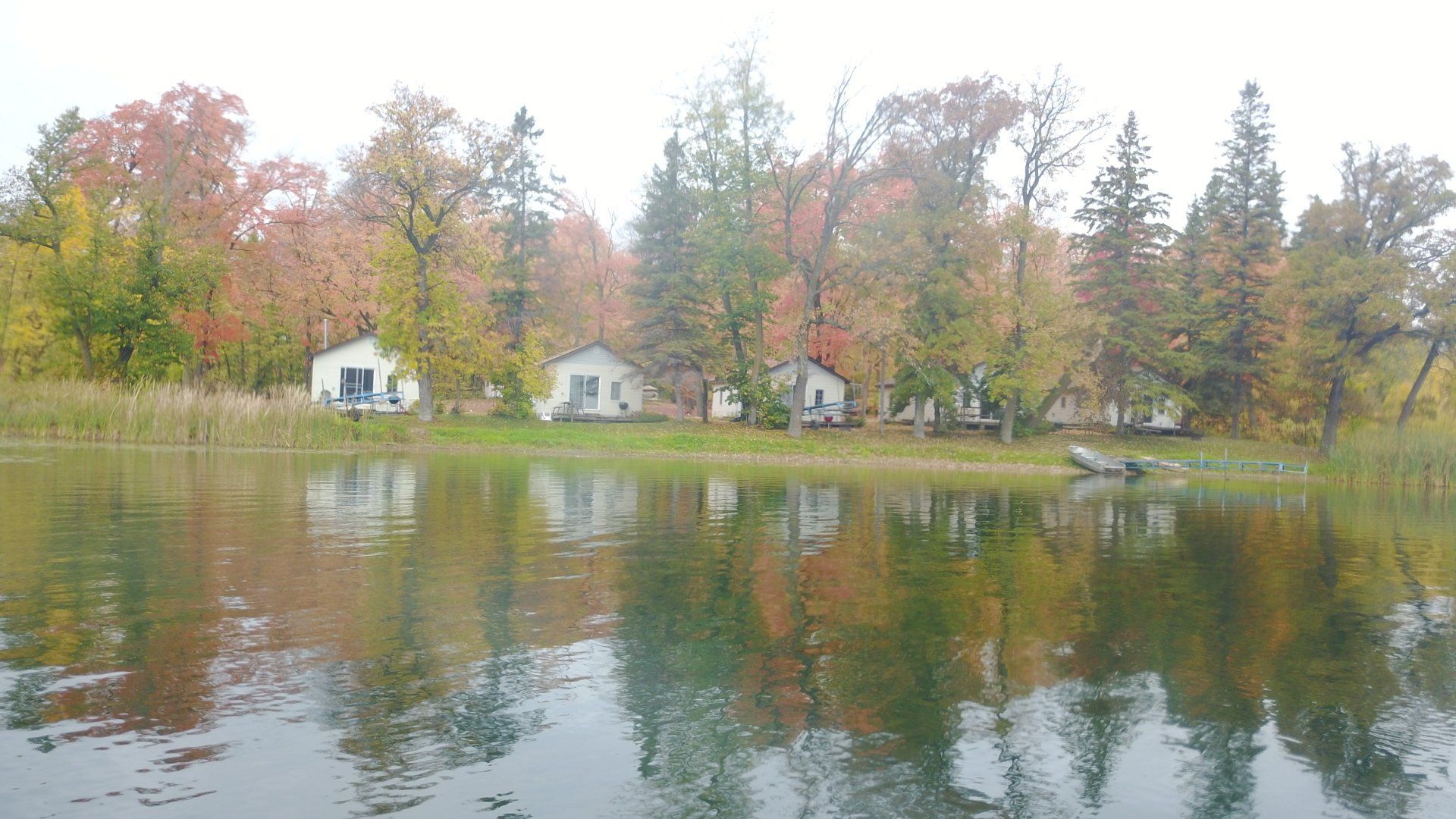 A lake surrounded by trees and houses on a cloudy day.