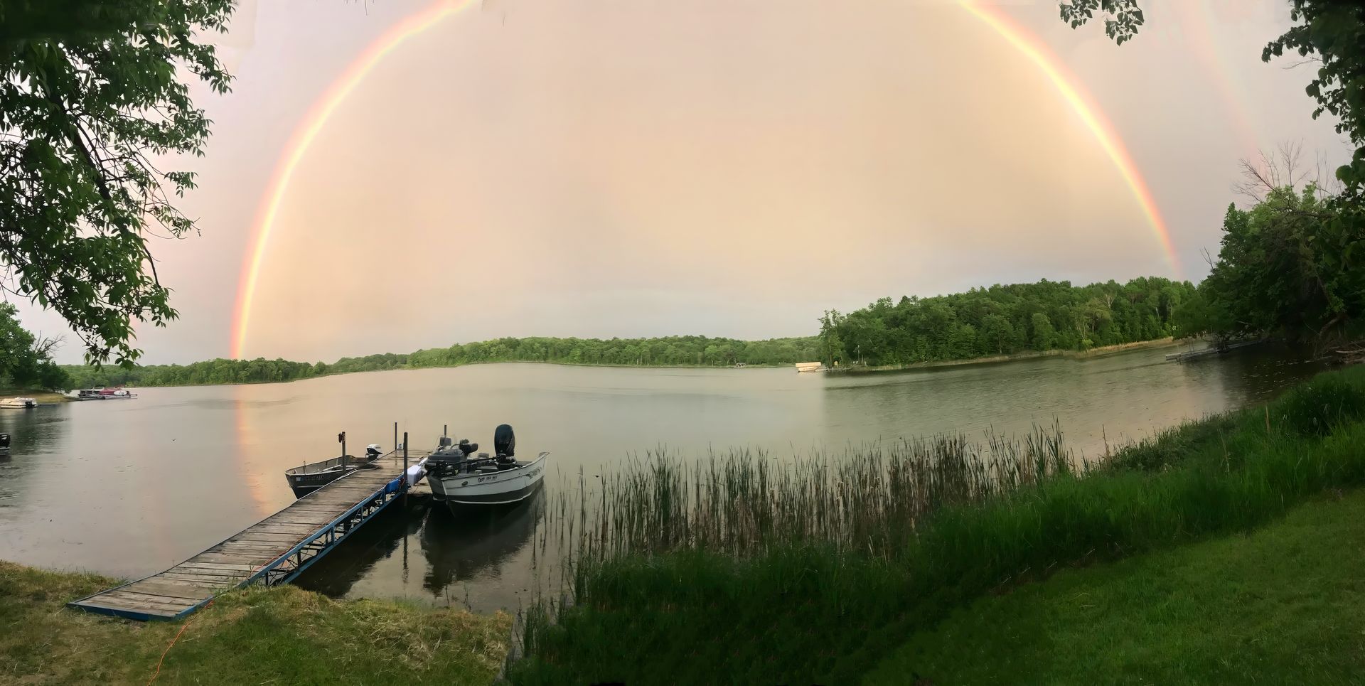A rainbow over a lake with boats docked at the dock.