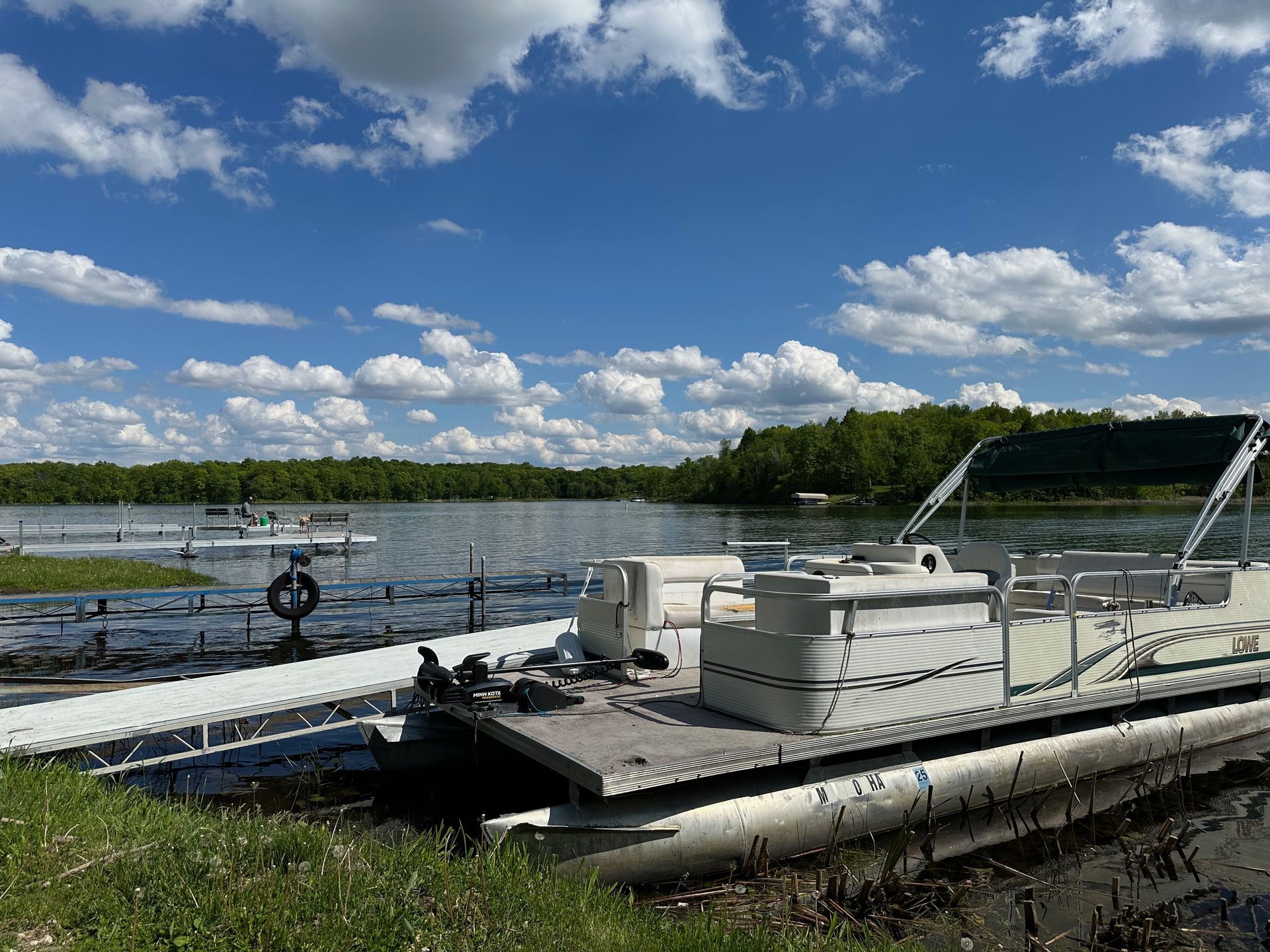 A pontoon boat is docked at a dock on a lake.
