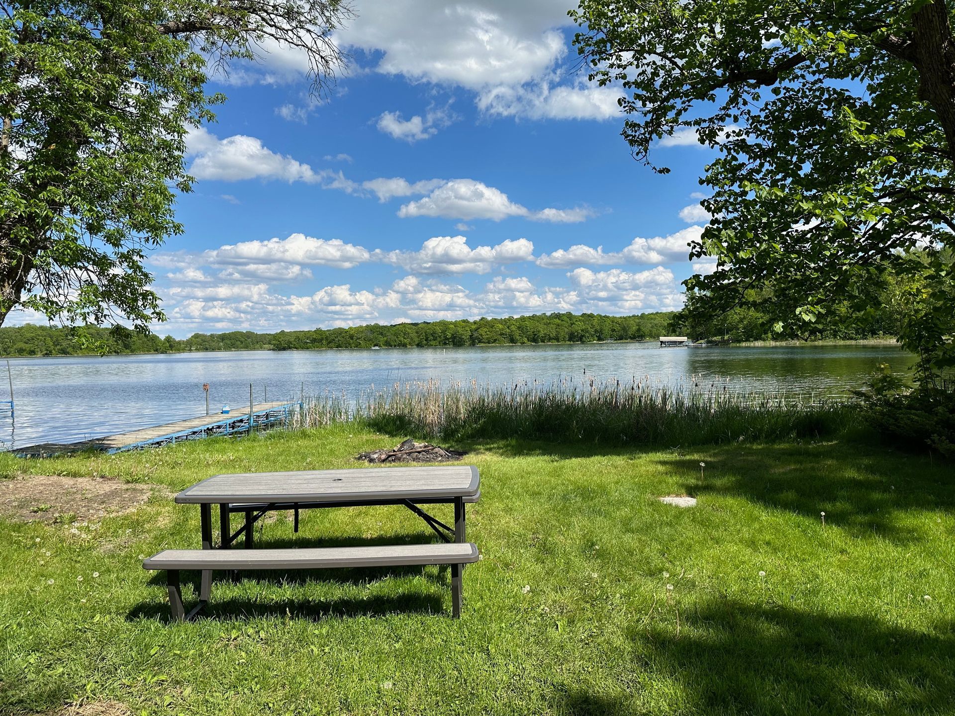 A picnic table is sitting in the grass next to a lake.