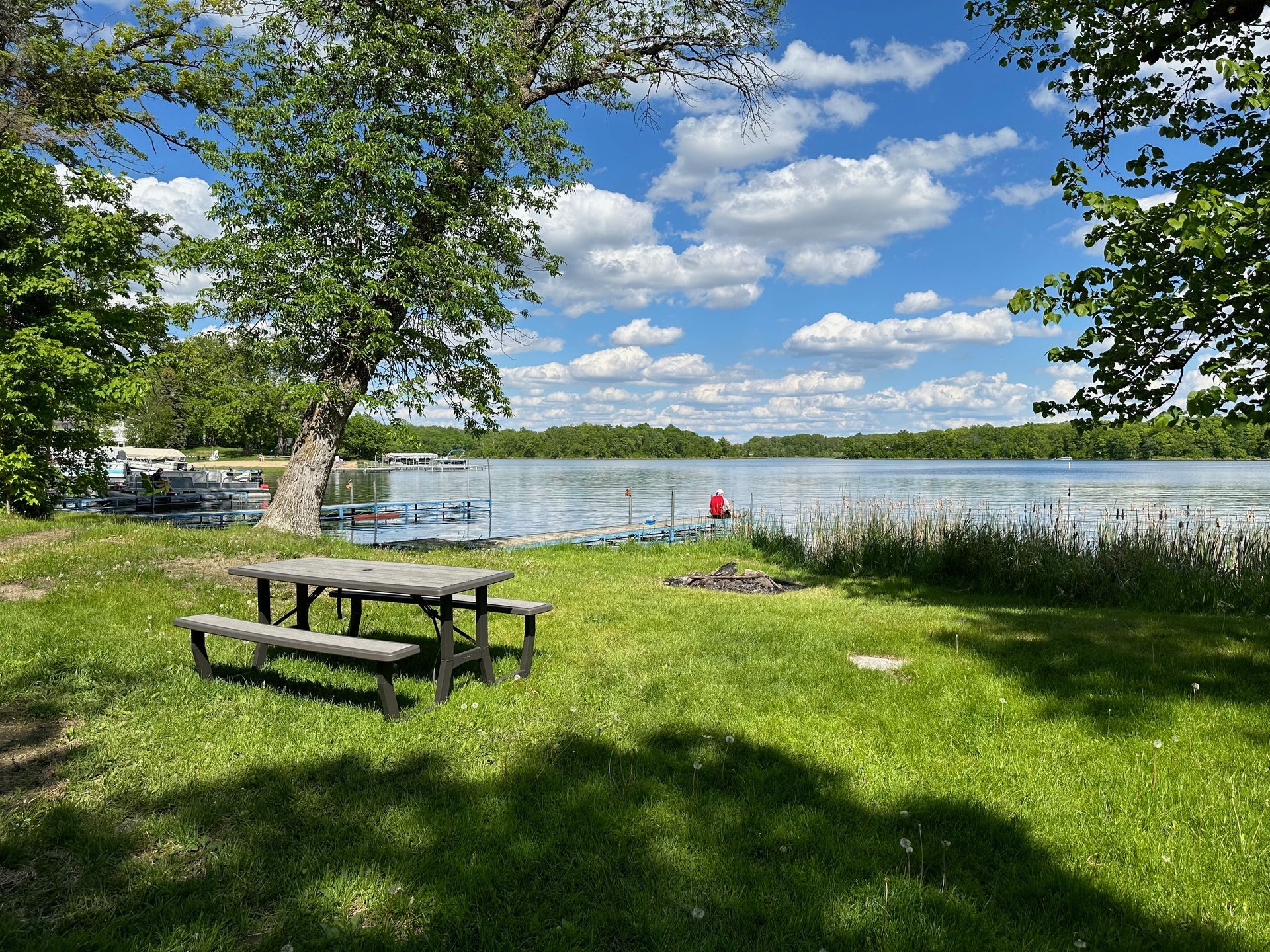 A picnic table is sitting in the grass next to a lake.