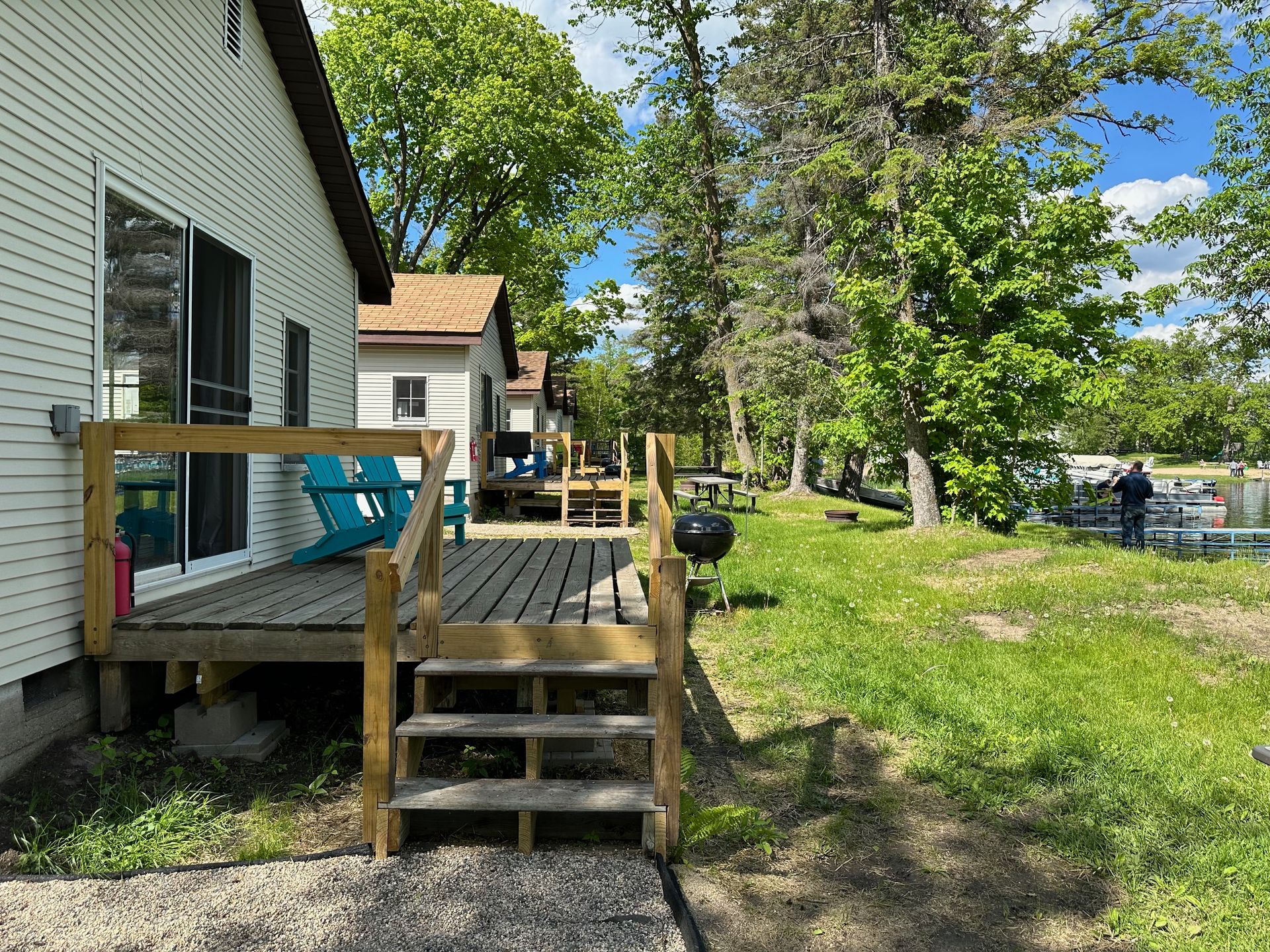 A white house with a wooden deck and stairs in front of it.