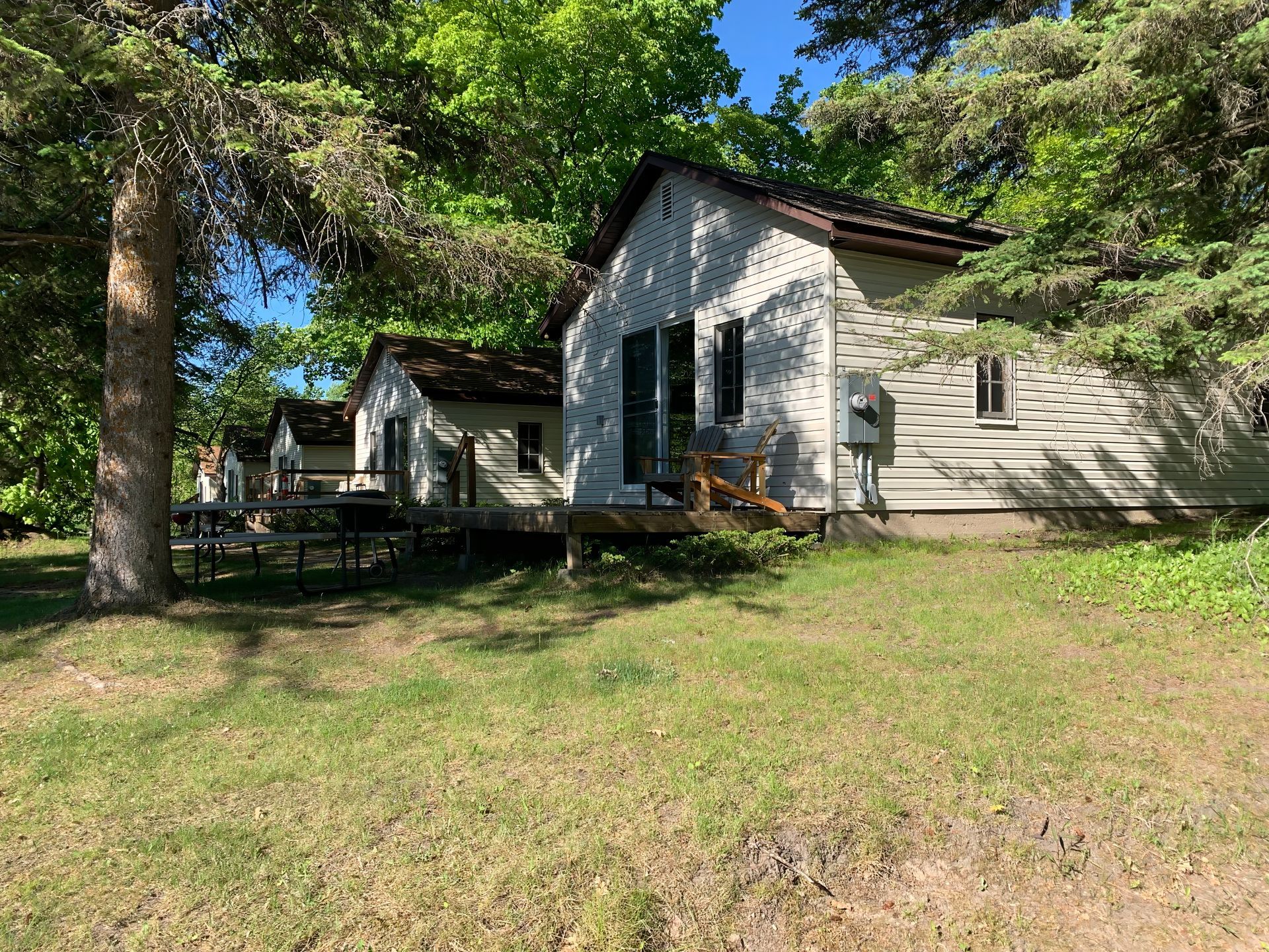 A white house is sitting in the middle of a grassy field surrounded by trees.