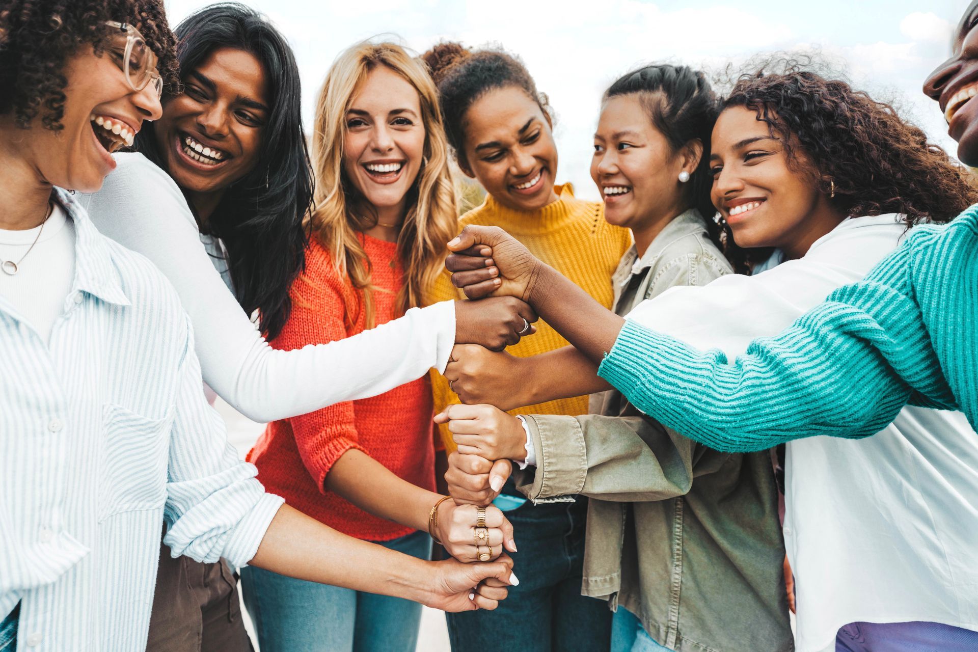 Group of diverse people smiling and bumping fists together.