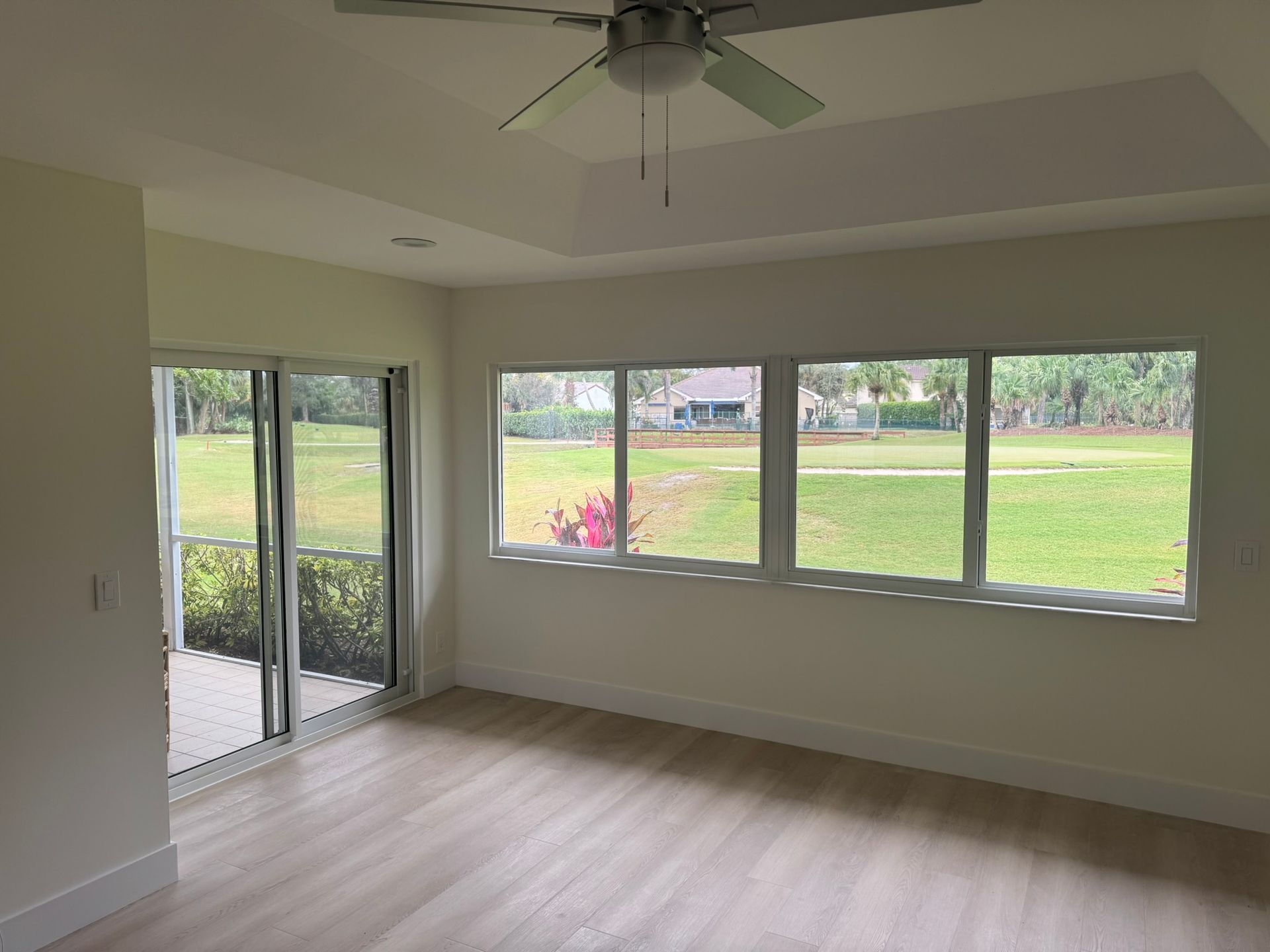Room with large windows overlooking a grassy yard and sliding glass doors. Lake Worth, FL