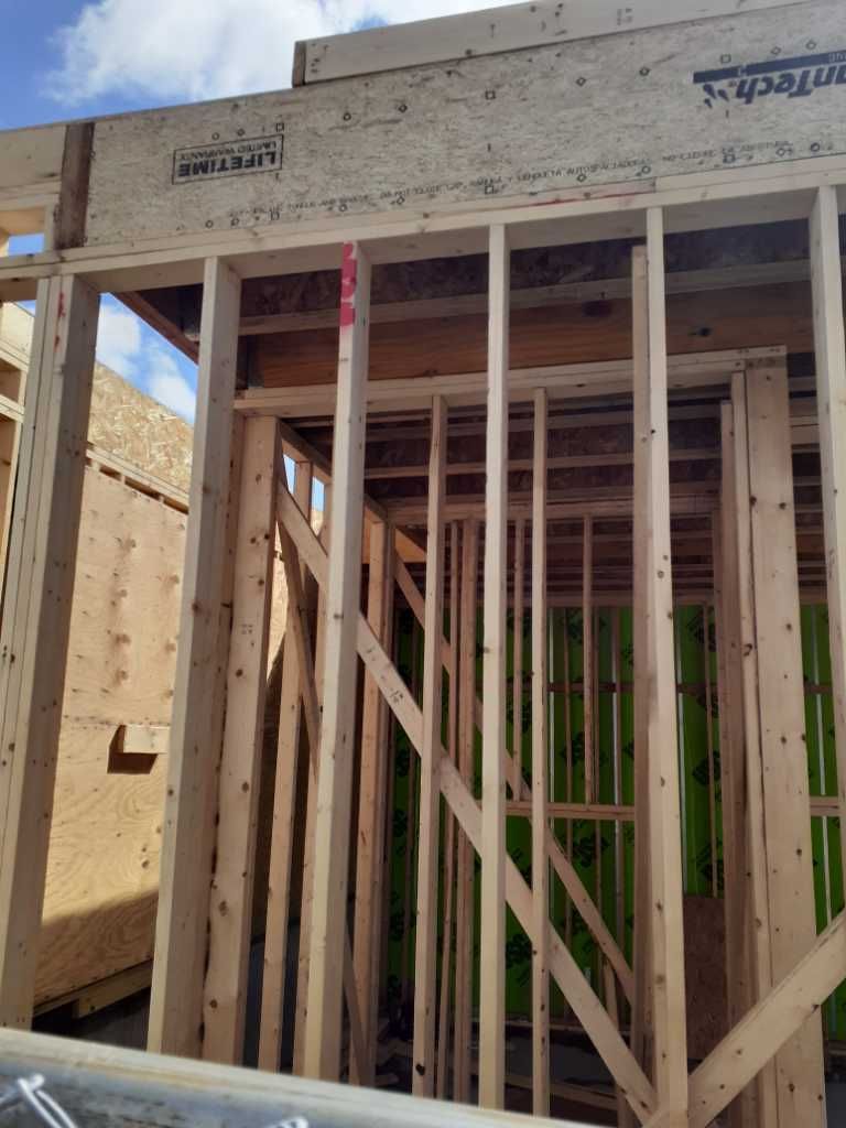 Wooden framing of a building under construction. Studs, headers, and sheathing are visible.