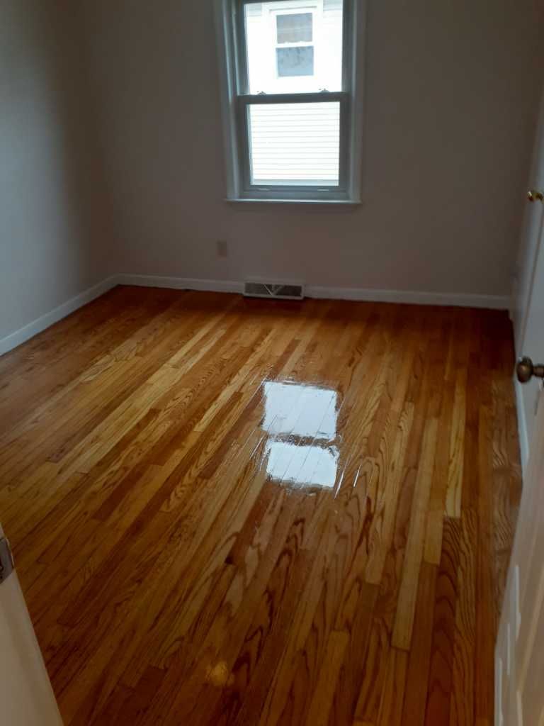Empty room with hardwood floor and window; sunlight shining on floor.