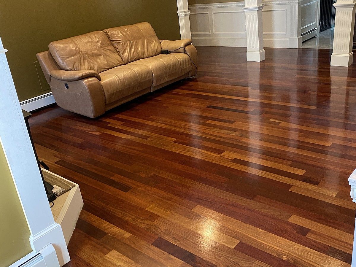 Brown hardwood floor in living room with leather couch.