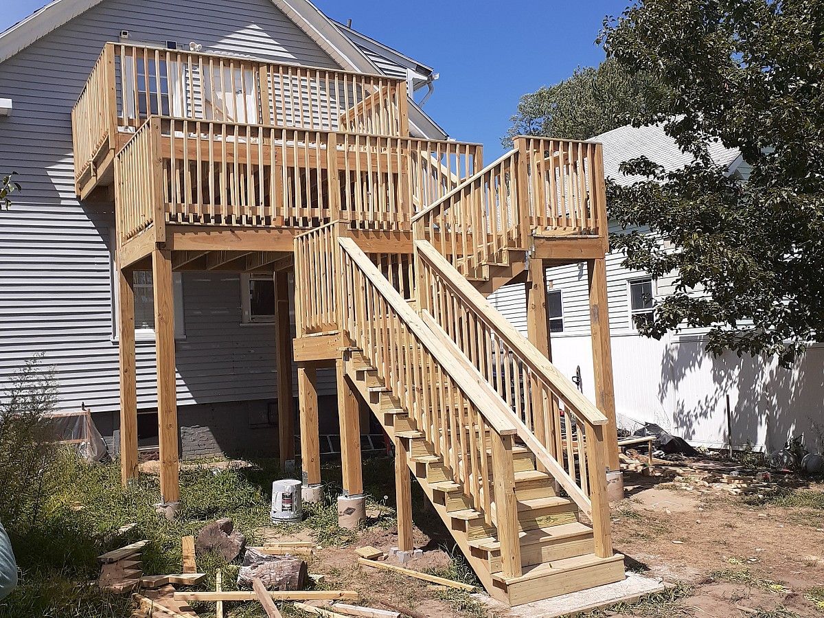 Wooden deck and stairs built on the side of a house. Sunny day.