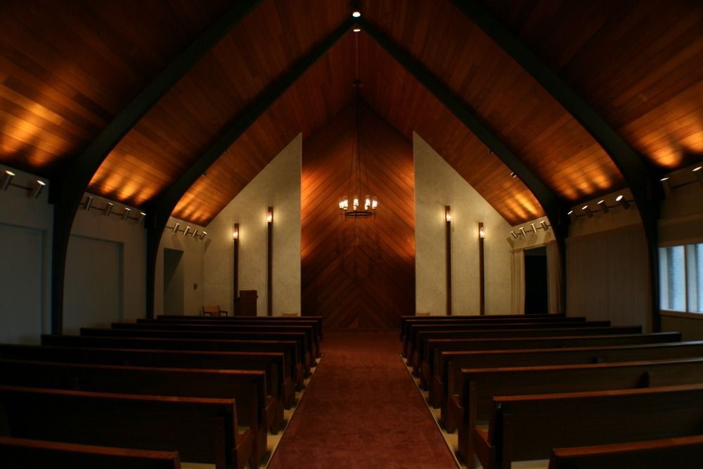 Dimly lit church interior with wooden pews facing a central altar and vaulted ceiling