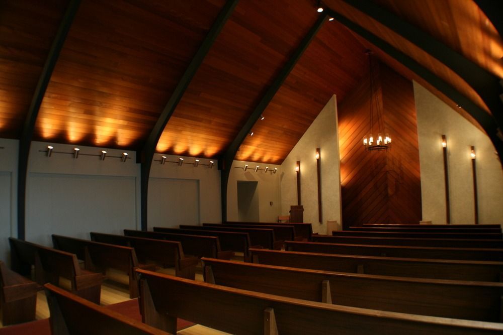 Empty church interior with wooden pews, vaulted wood ceiling, and warm lighting