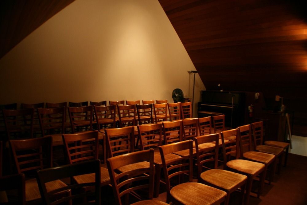Empty auditorium with rows of wooden chairs under warm stage lighting