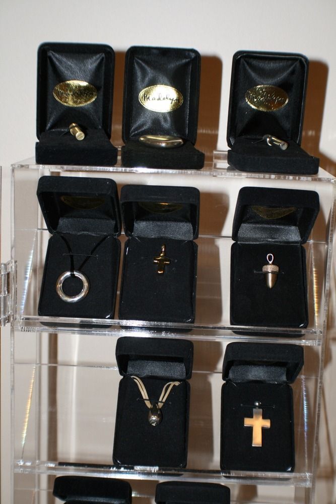 Display of jewelry in black velvet boxes on acrylic shelves, including rings, necklaces, and crosses.