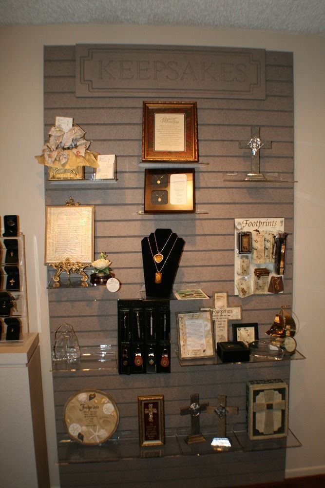 Wall-mounted display of assorted framed art, clocks, and decorative objects on gray slatwall shelves