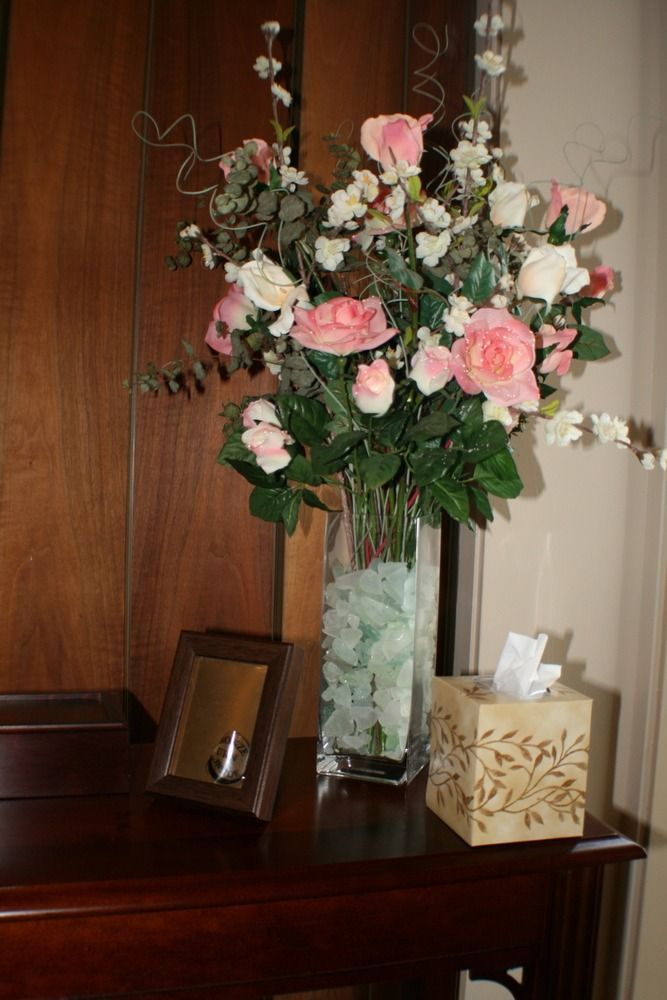 Tall floral arrangement with pink and white flowers in a glass vase on a dresser beside a framed photo and tissue box