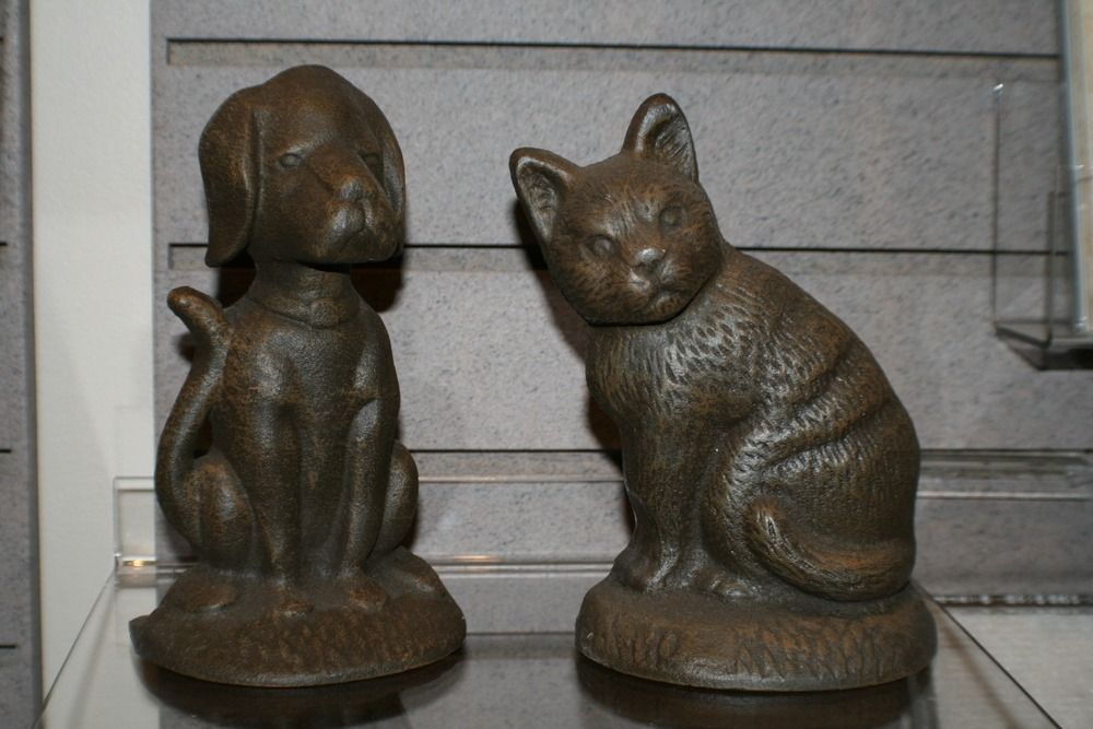 Two bronze animal statues, a seated dog and cat, on display shelves