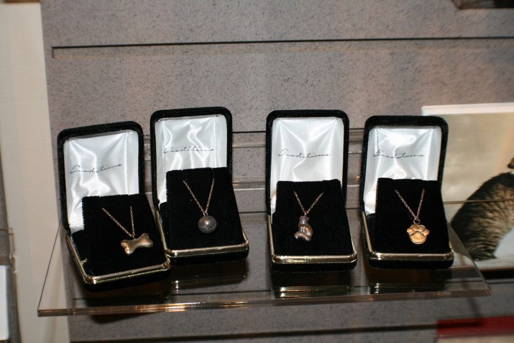 Four jewelry boxes displaying gold necklaces on a glass shelf