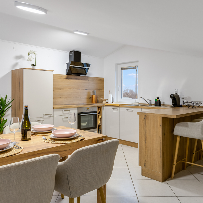 Cozy kitchen with wooden accents. Dining table set with plates, a breakfast bar, and chairs.