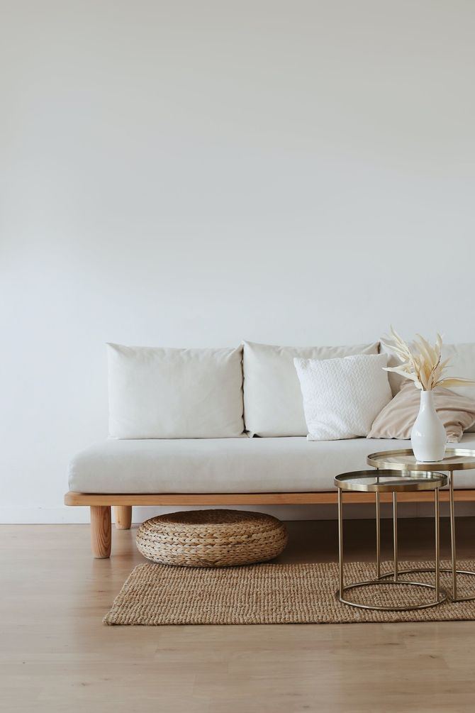 A neutral-toned living room with a beige couch, pillows, round wicker basket, and small table.