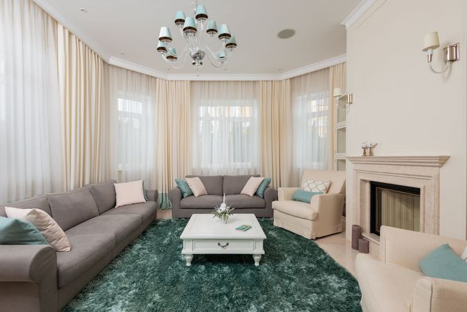 Living room with gray sofas, cream chairs, a fireplace, and a teal rug.