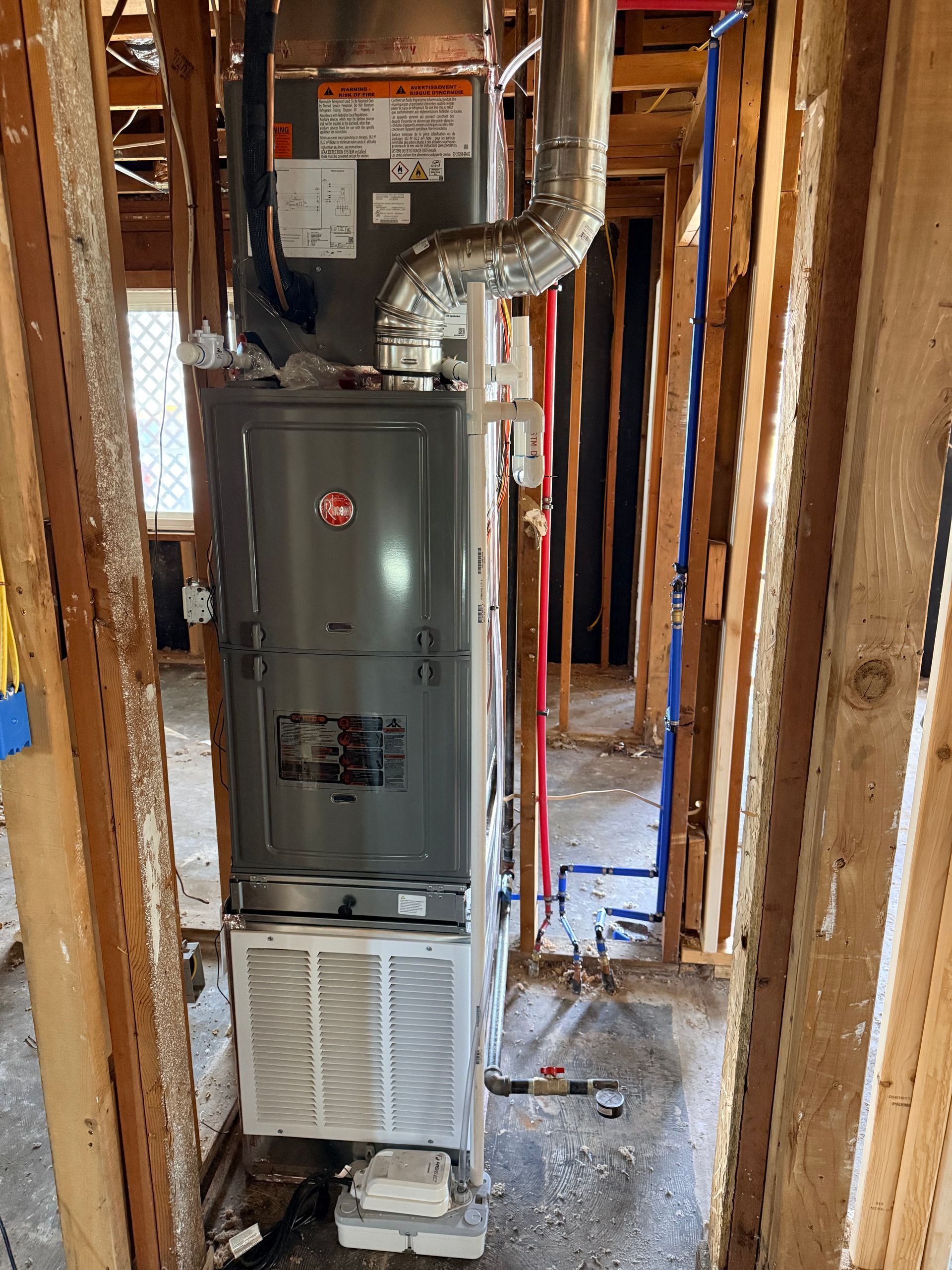 High-efficiency furnace in a framed-in construction area with exposed ductwork and wiring