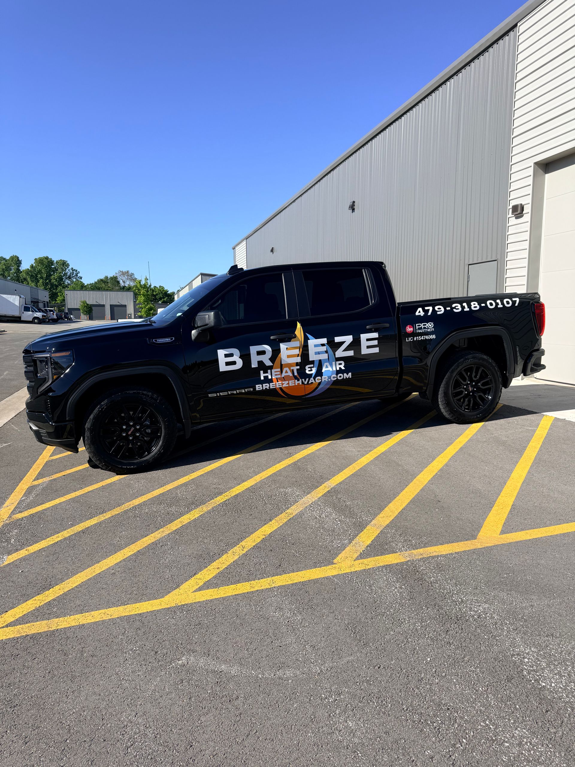 Black Breezeway truck parked by a white building on yellow-striped pavement.