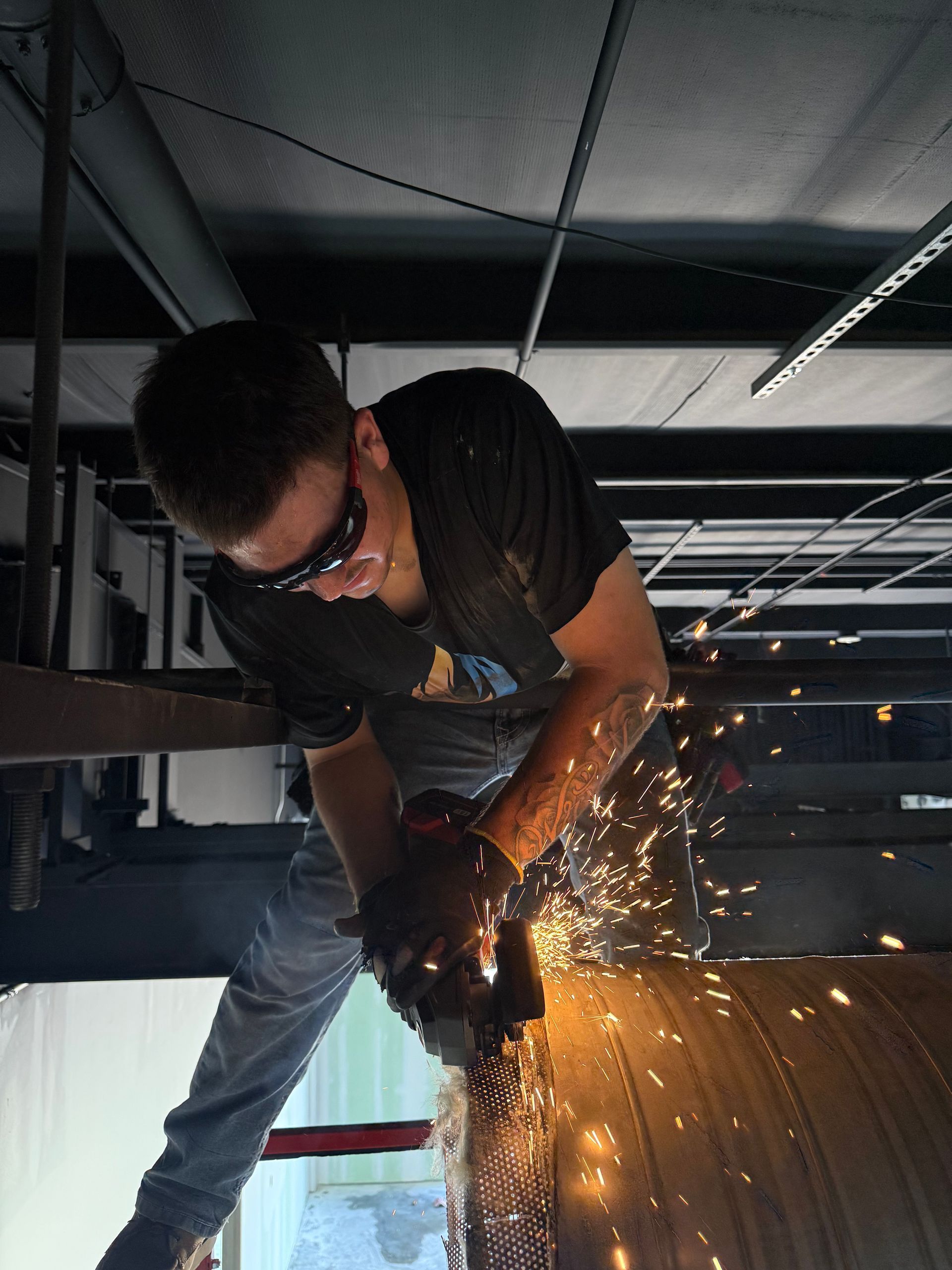 Worker grinding metal, sending sparks in an indoor construction setting.