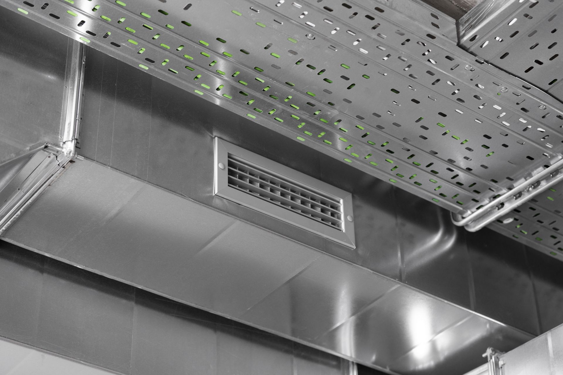 Ceiling HVAC vent and ductwork in an industrial interior, viewed in black and white.
