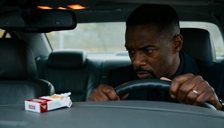 real estate agent sitting in his car between showings in Columbus staring at a pack of cigarettes on the dashboard tempted to smoke but showing restraint