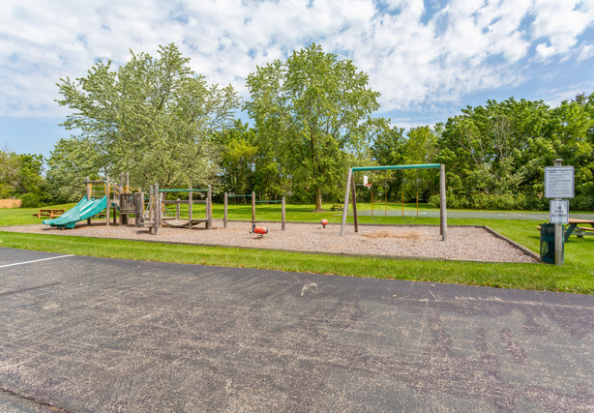 A playground with a slide and swings in a park.