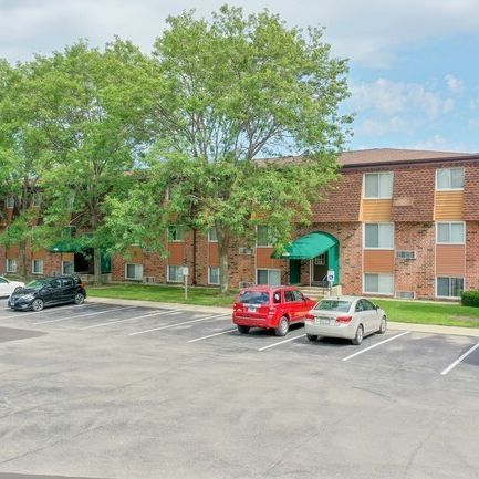 A parking lot with cars parked in front of a brick apartment building