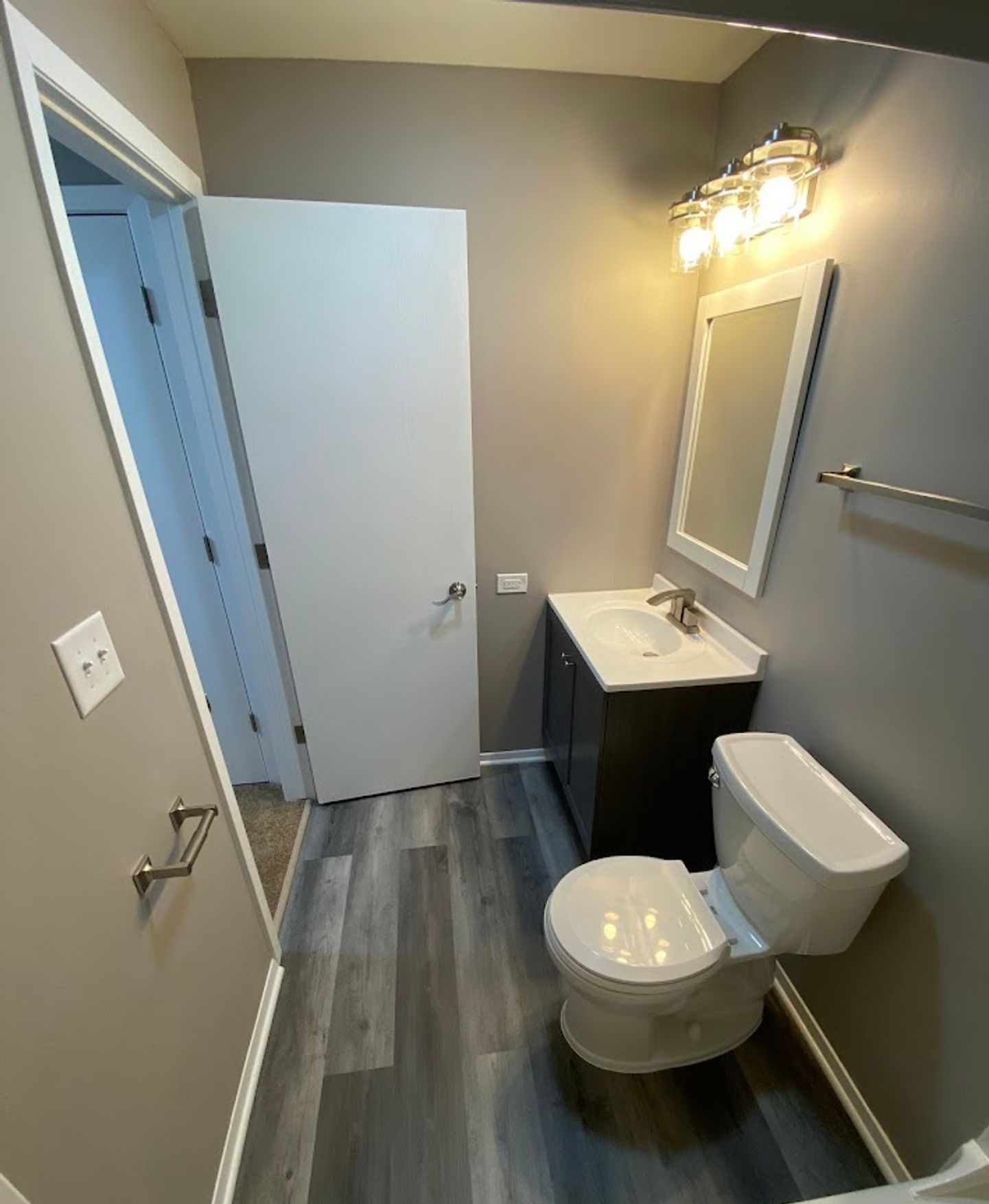 A bathroom with a toilet , sink and mirror.