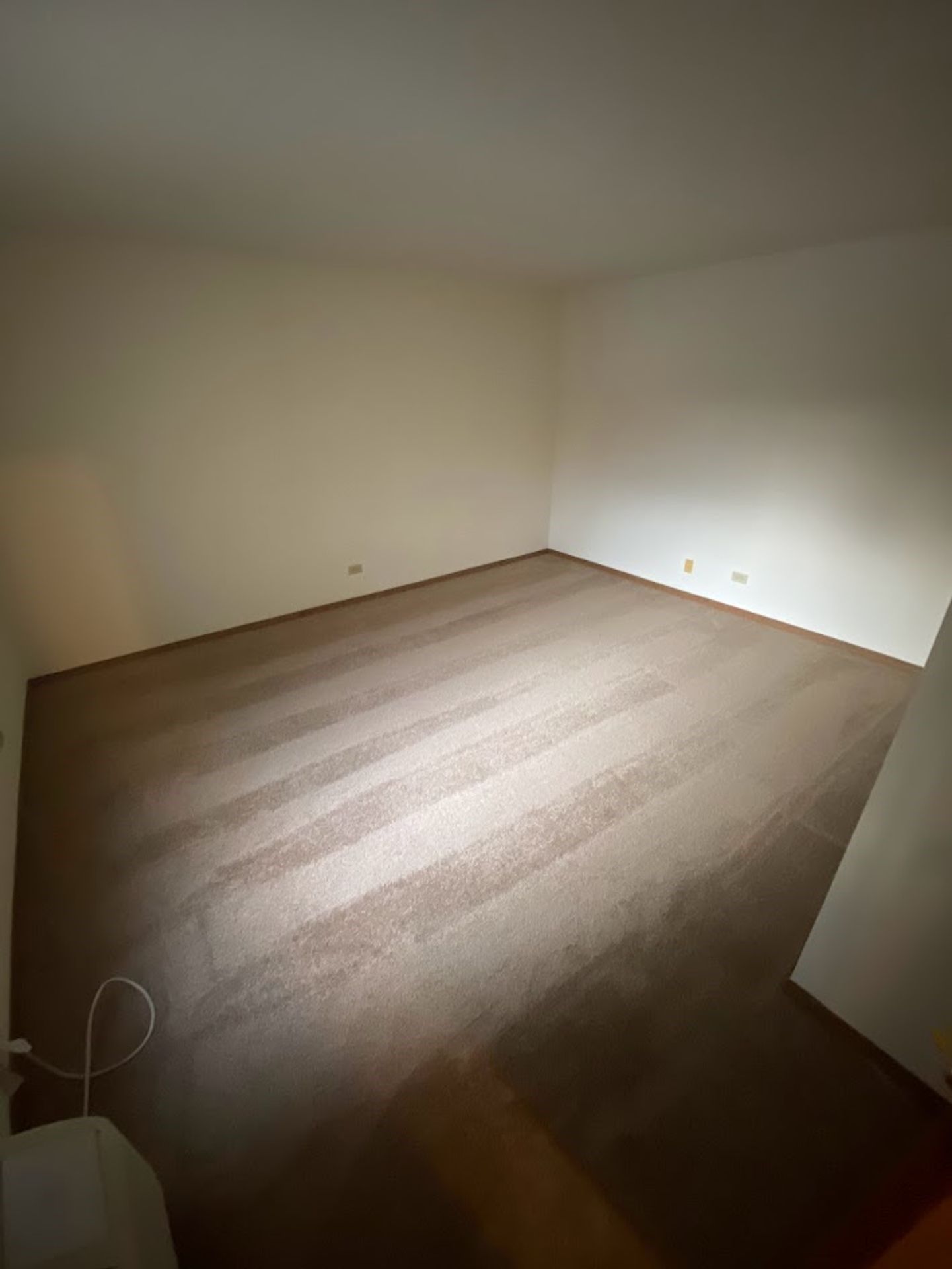 An empty room with a carpeted floor and white walls.