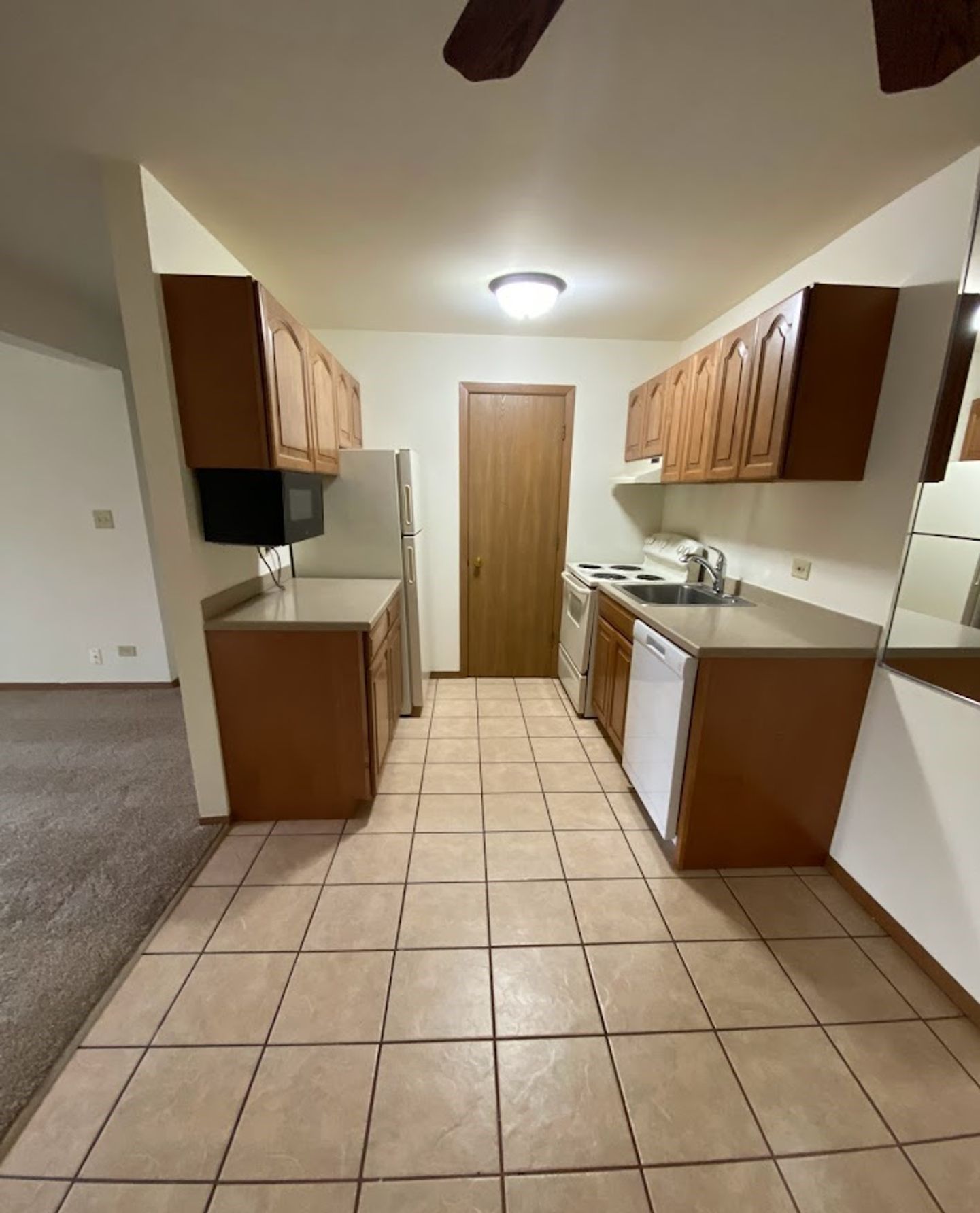 A kitchen with wooden cabinets and a tiled floor
